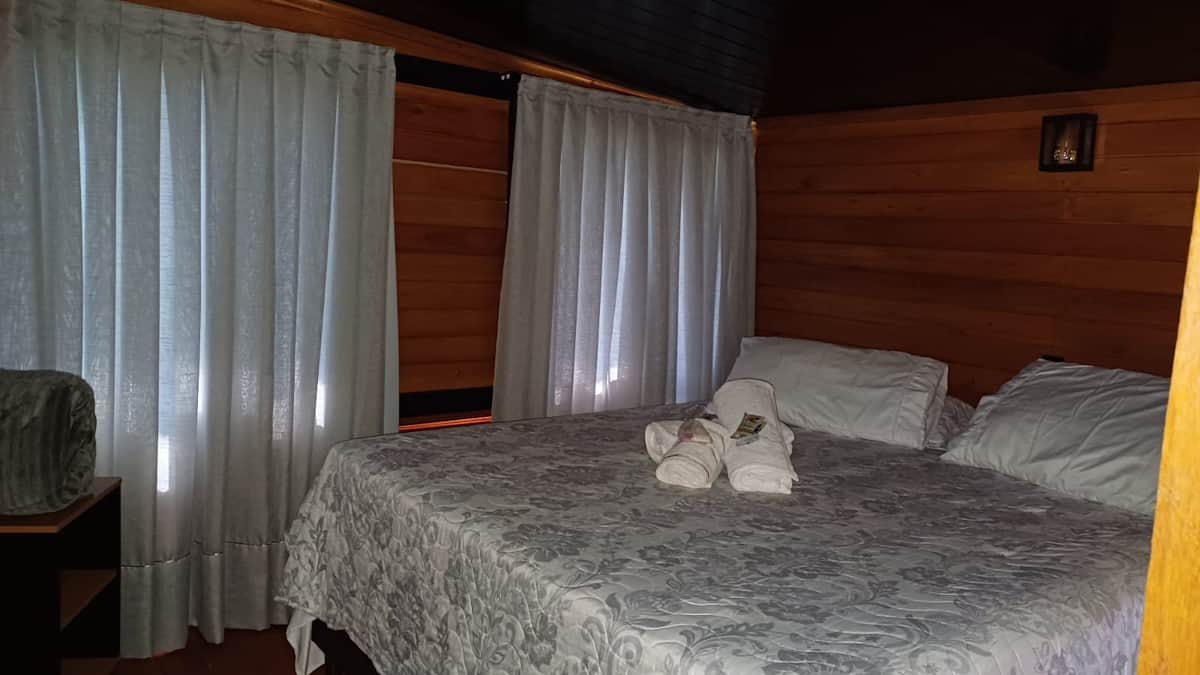 Quarto da Cabana Angillyn com cortinas e roupa de cama branca
